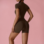 Person wearing a brown bodysuit against a pink background