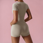 Person wearing a beige bodysuit against a pink background
