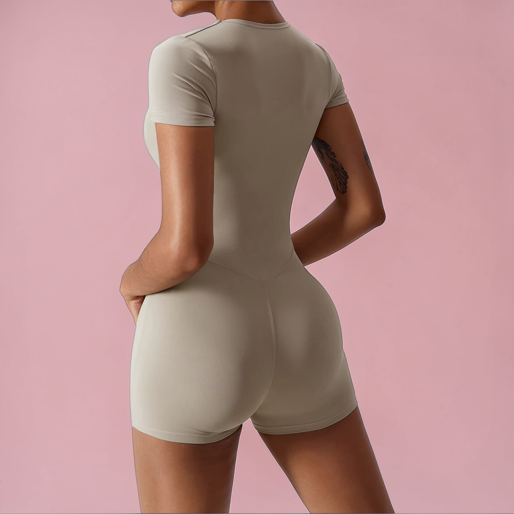 Person wearing a beige bodysuit against a pink background