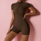 Person wearing a brown bodysuit against a pink background