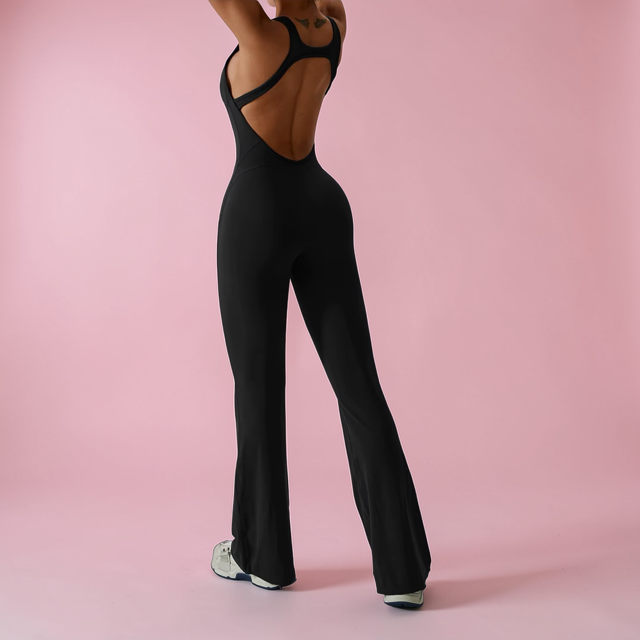 Person wearing a black jumpsuit on a pink background