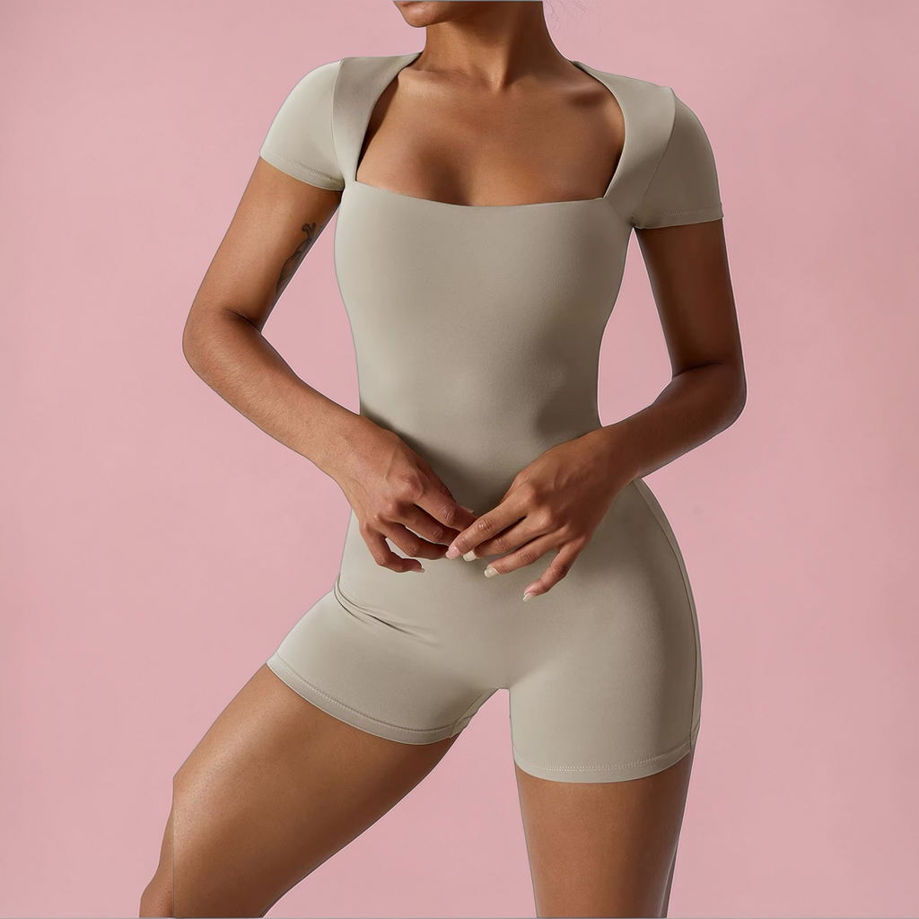 Person wearing a beige bodysuit against a pink background