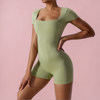 Person wearing a green bodysuit against a pink background