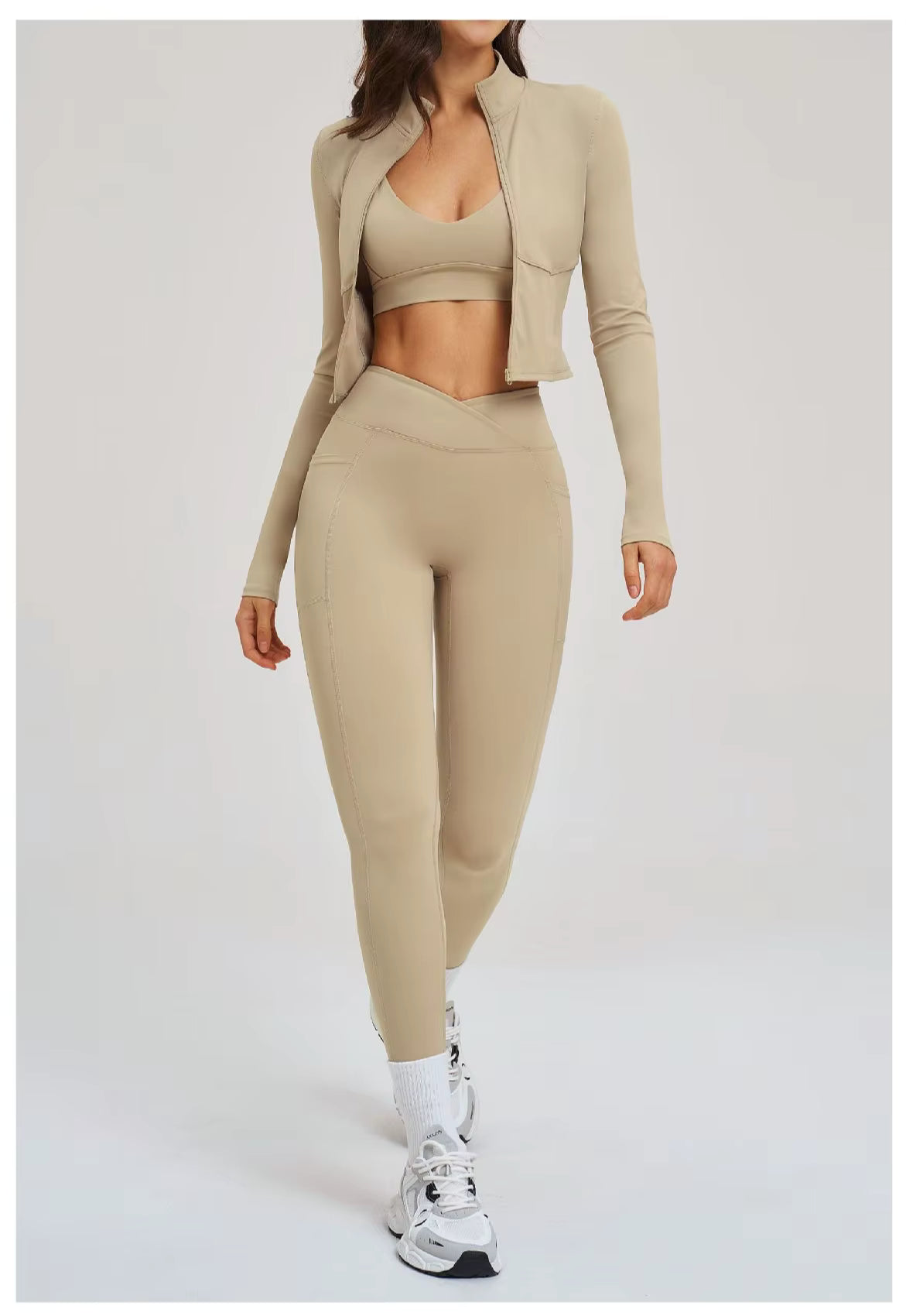 Woman wearing a beige athletic outfit with white sneakers on a light gray background