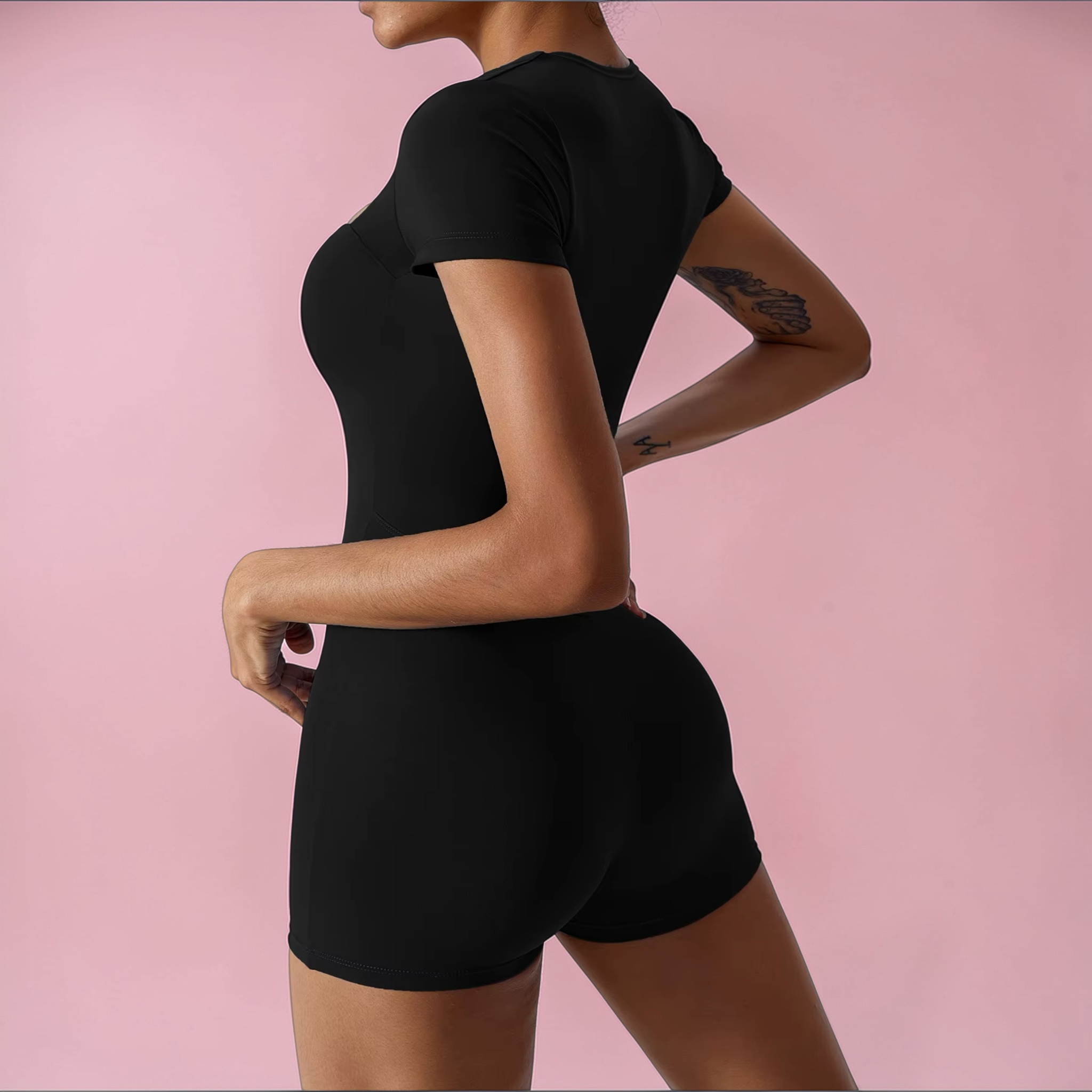 Person wearing a black athletic outfit on a pink background