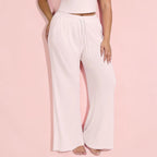 Light pink lounge pants worn by a person on a pink background