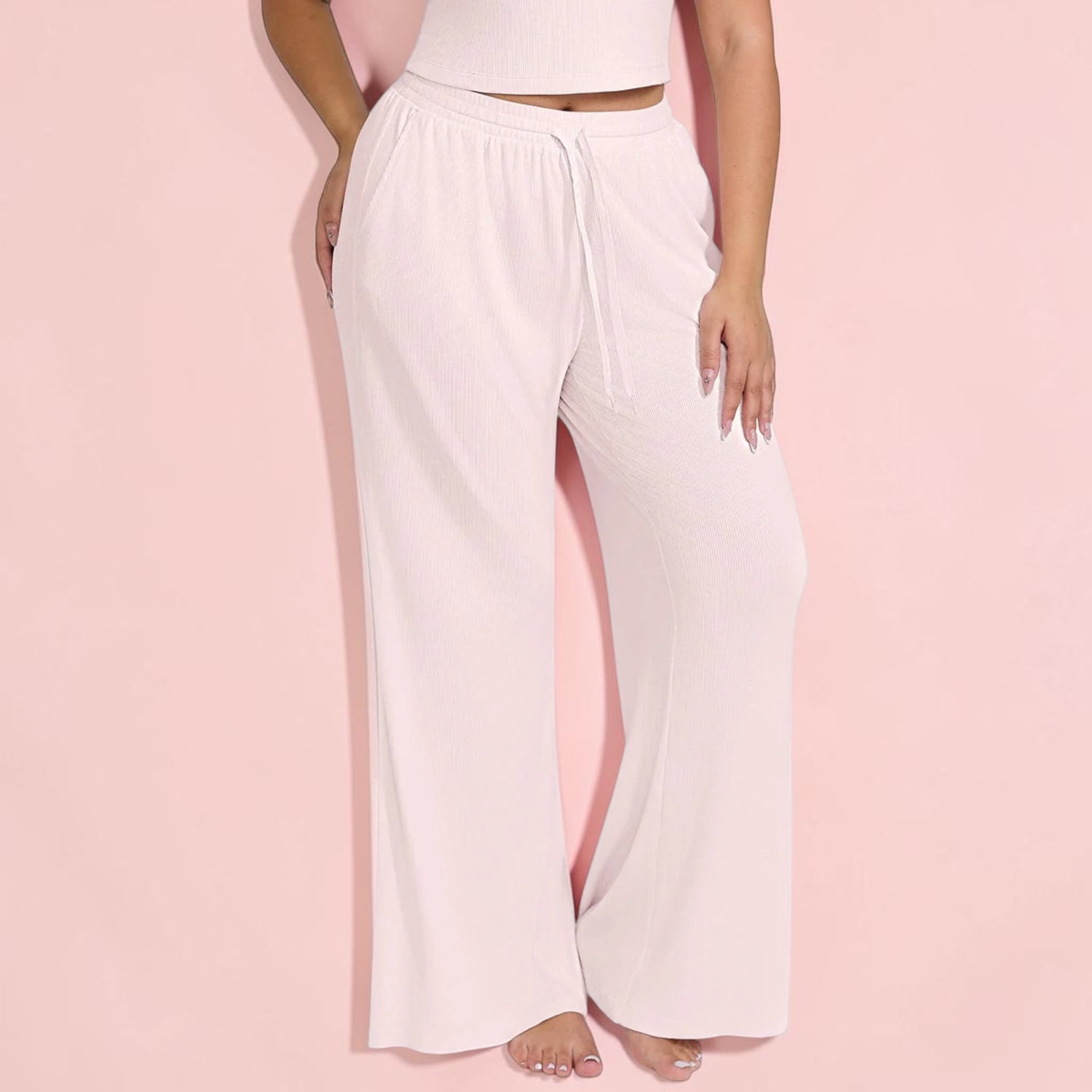 Light pink lounge pants worn by a person on a pink background