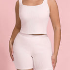Person wearing a light pink tank top and shorts set on a pink background