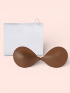Brown silicone bralette on a light pink background with a white pouch.