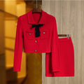 A bright red 2-piece skirt set with a bow sweater top and mini design lady knitted suits, displayed on a hanger.