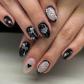 Nails with black and silver decorative designs on a neutral background
